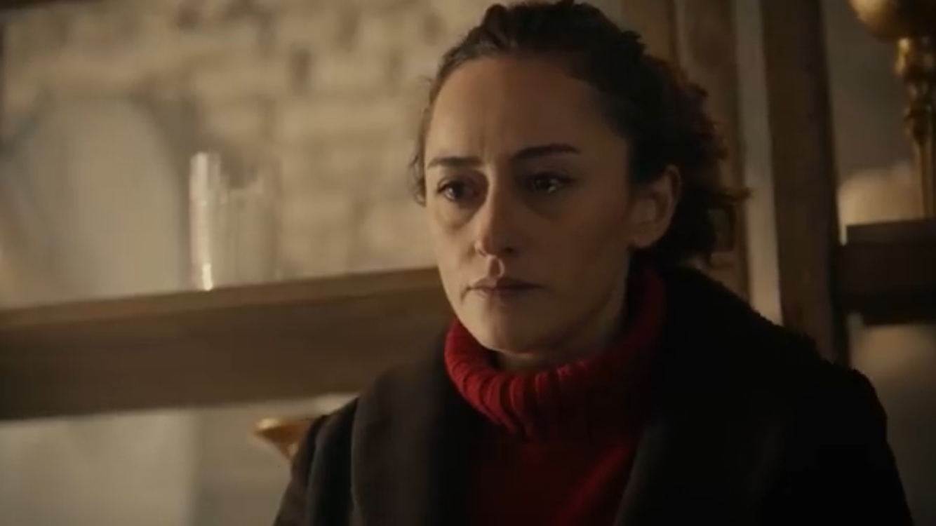 Bir Deli Sevda — A woman wearing a red scarf in a softly lit shop.
