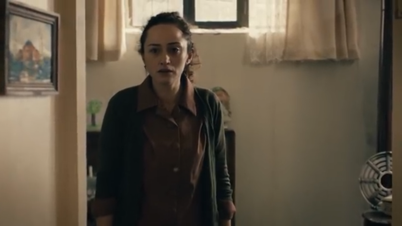Bir Deli Sevda — A woman standing beneath a small window.