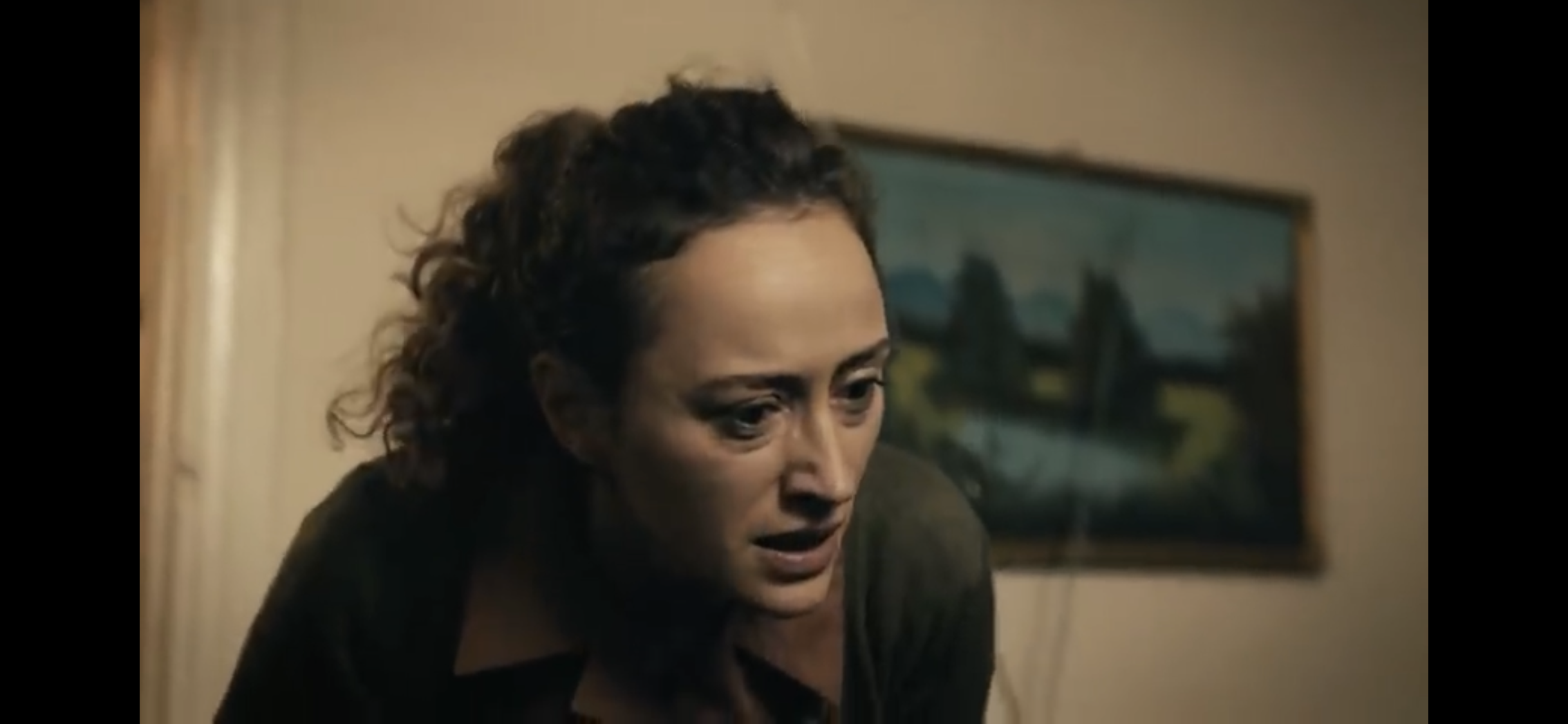Bir Deli Sevda — A woman leaning forward in a softly lit room.