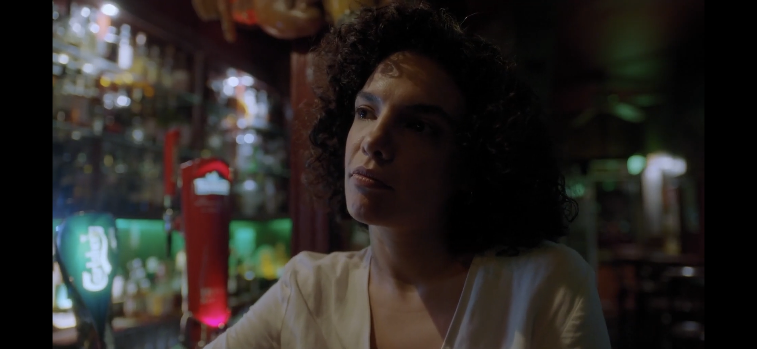 Diyalog — Close-up of a woman at a dimly lit bar.