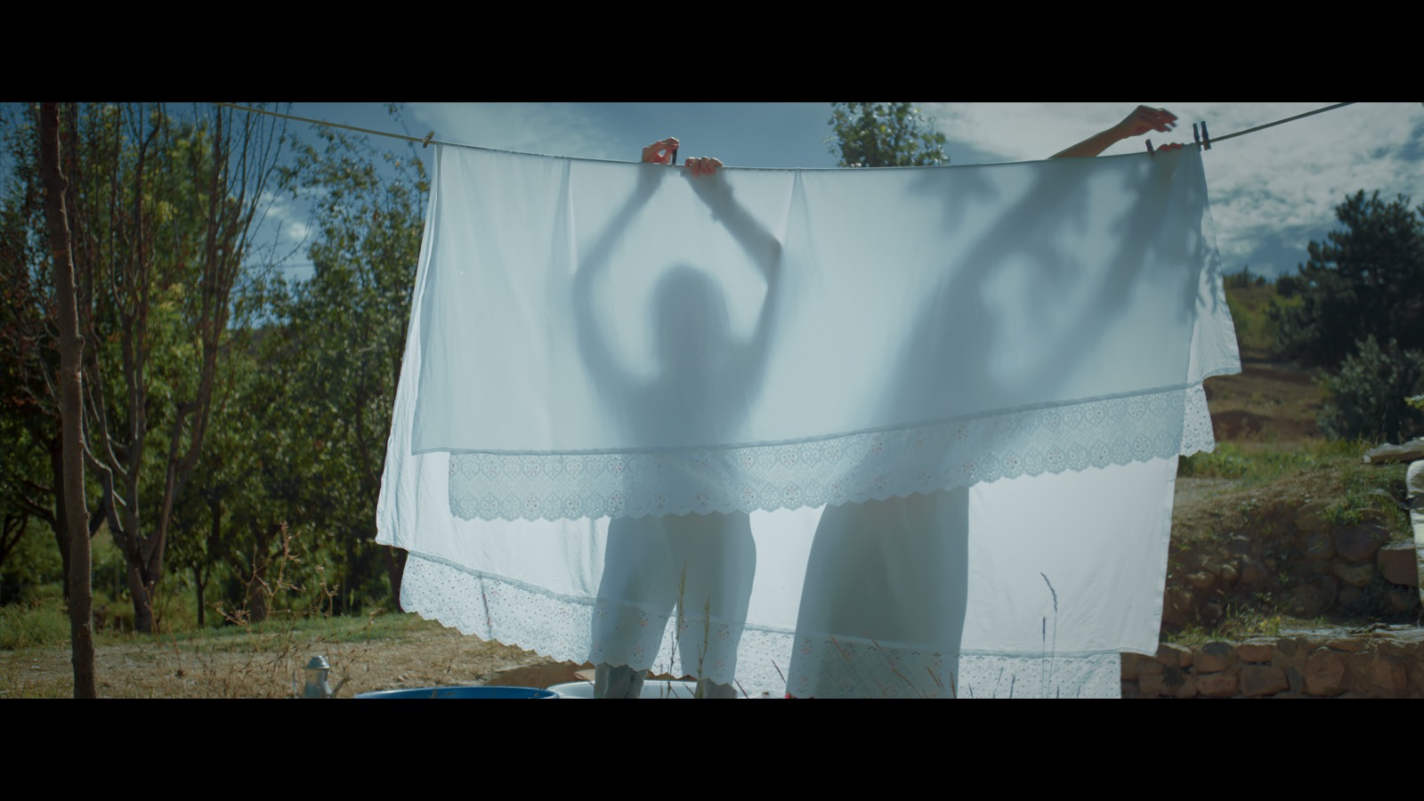 Kabahat — Silhouettes behind a white sheet hanging in sunlight.