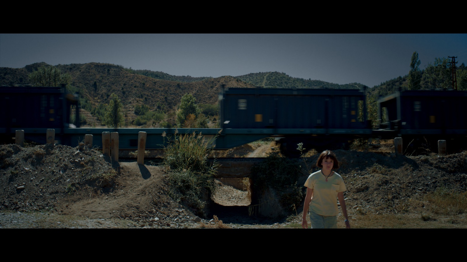 Kabahat — A girl beside a railway as a freight train passes.