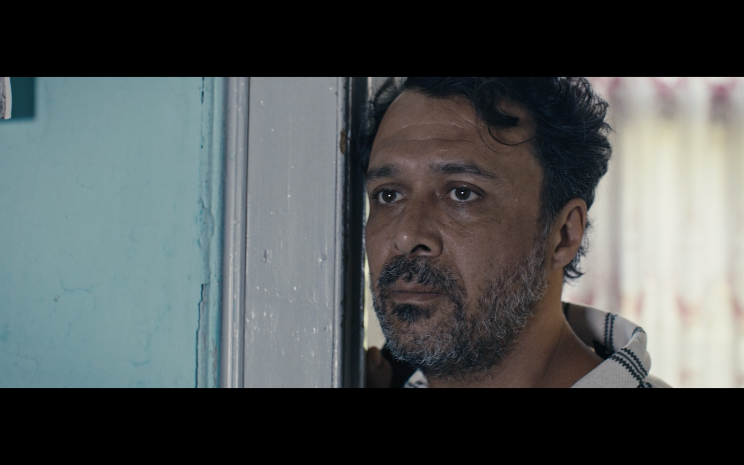 Kavanoz — A man looking out from a blue-painted doorway.