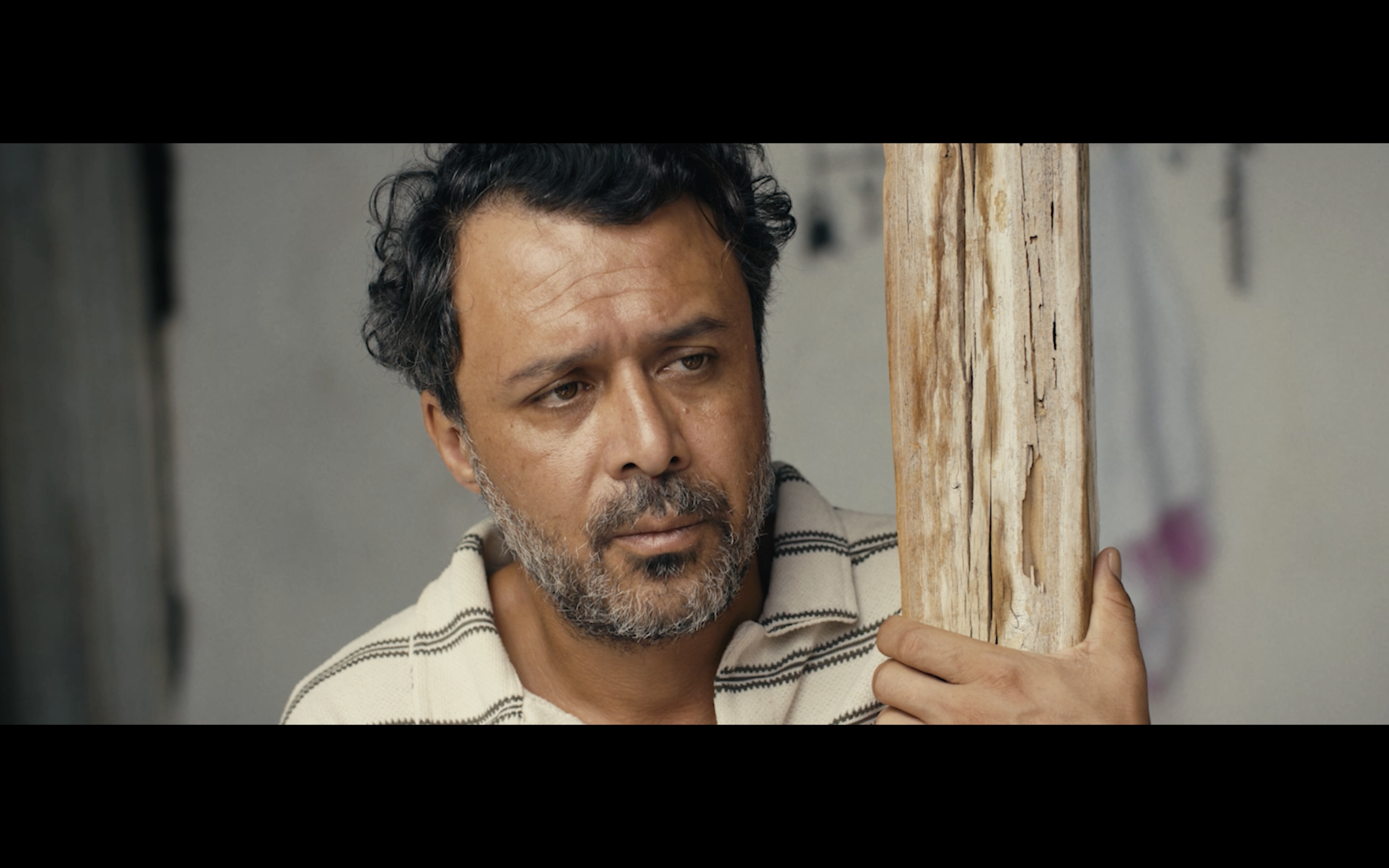 Kavanoz — A man leaning against a weathered wooden door frame.