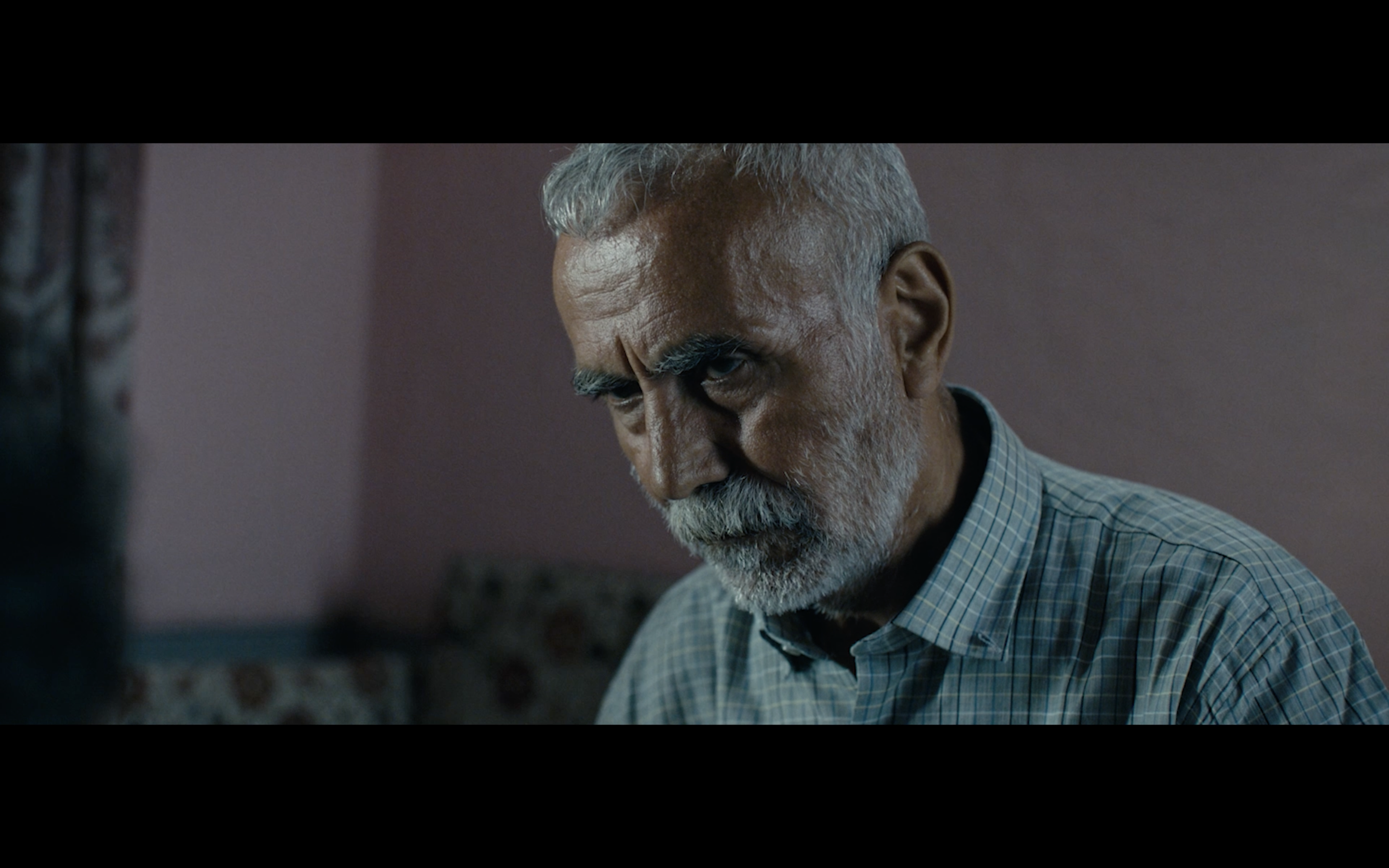 Kavanoz — Close-up of a grey-haired man indoors.