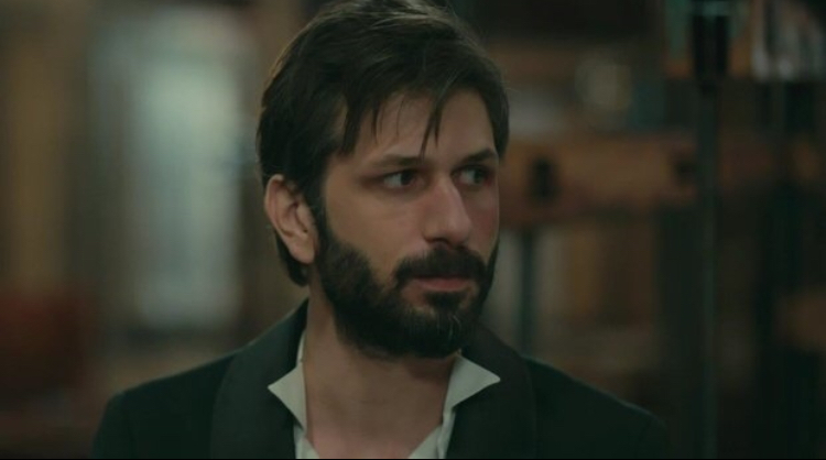 Masum Değiliz — A bearded man in a dark jacket indoors.